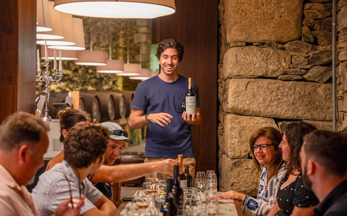 Tourists with guide tasting wine in Douro wine cellar.