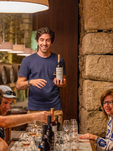Tourists with guide tasting wine in Douro wine cellar.
