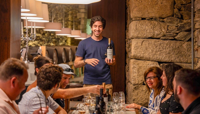 Tourists with guide tasting wine in Douro wine cellar.
