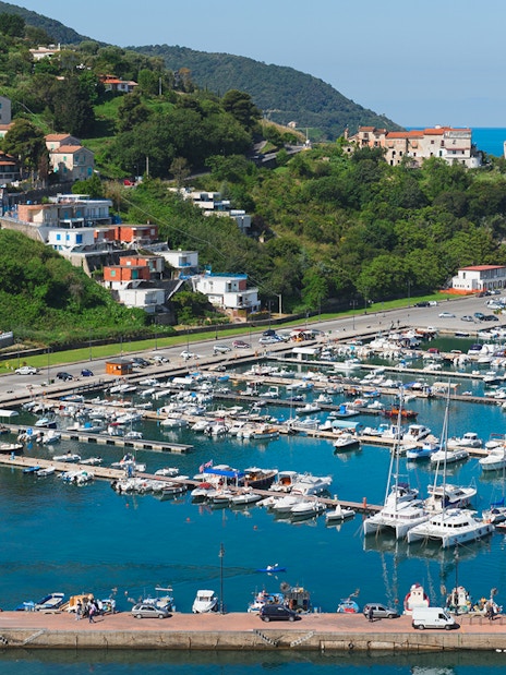 Amalfi Coast marina with colorful hillside buildings and boats docked in the harbor.