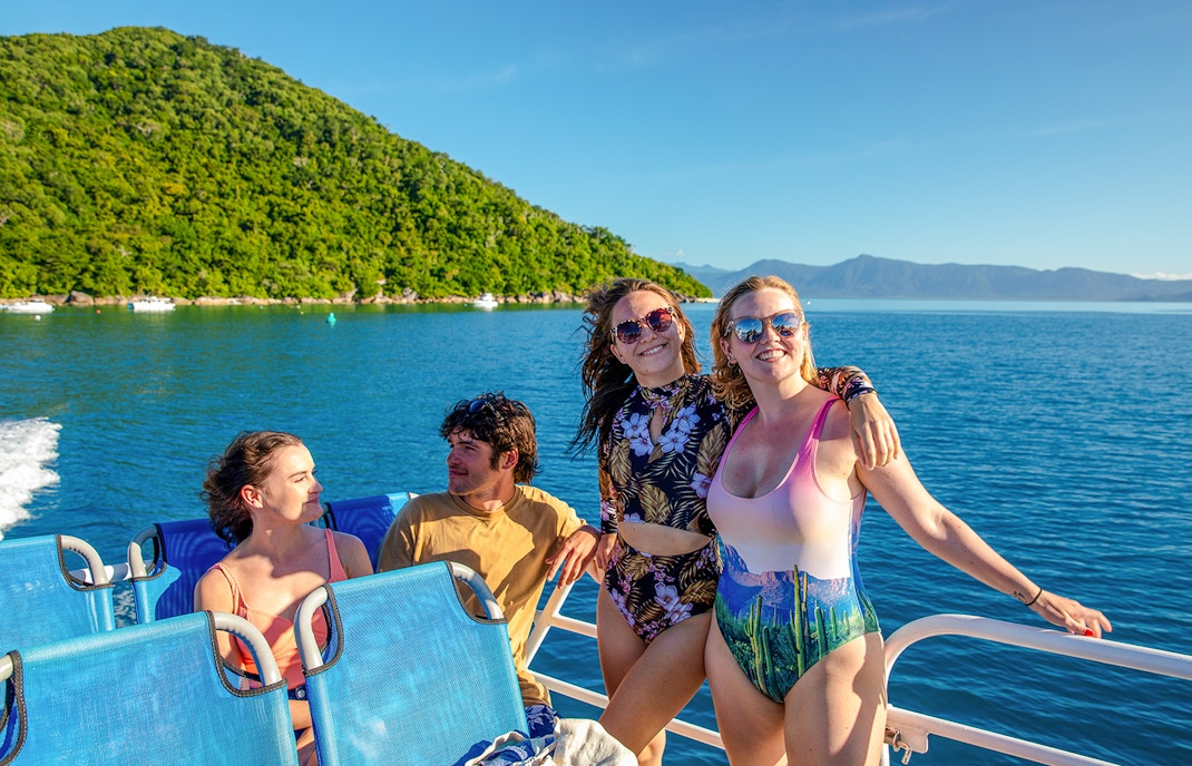 Group enjoying a boat ride from Cairns to Fitzroy Island with lush hills and ocean views.