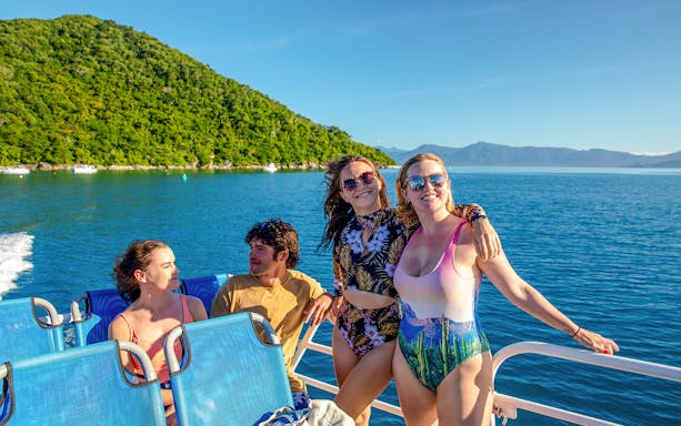 Group enjoying a boat ride from Cairns to Fitzroy Island with lush hills and ocean views.