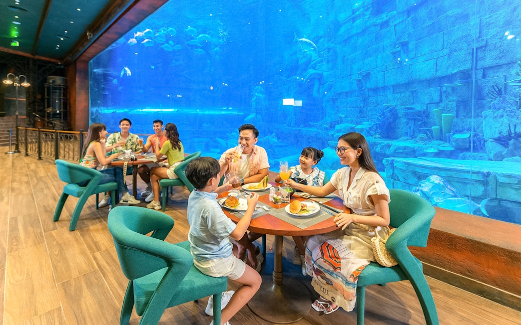 Guests dining at a table in front of a large aquarium.