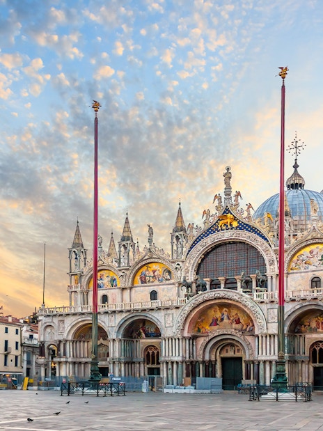 St. Mark's Basilica in Venice, Italy, with ornate facade and domes at sunset.
