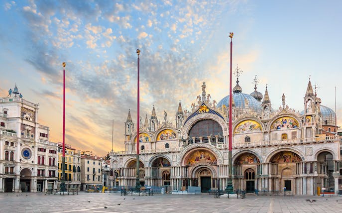 St. Mark's Basilica in Venice, Italy, with ornate facade and domes at sunset.