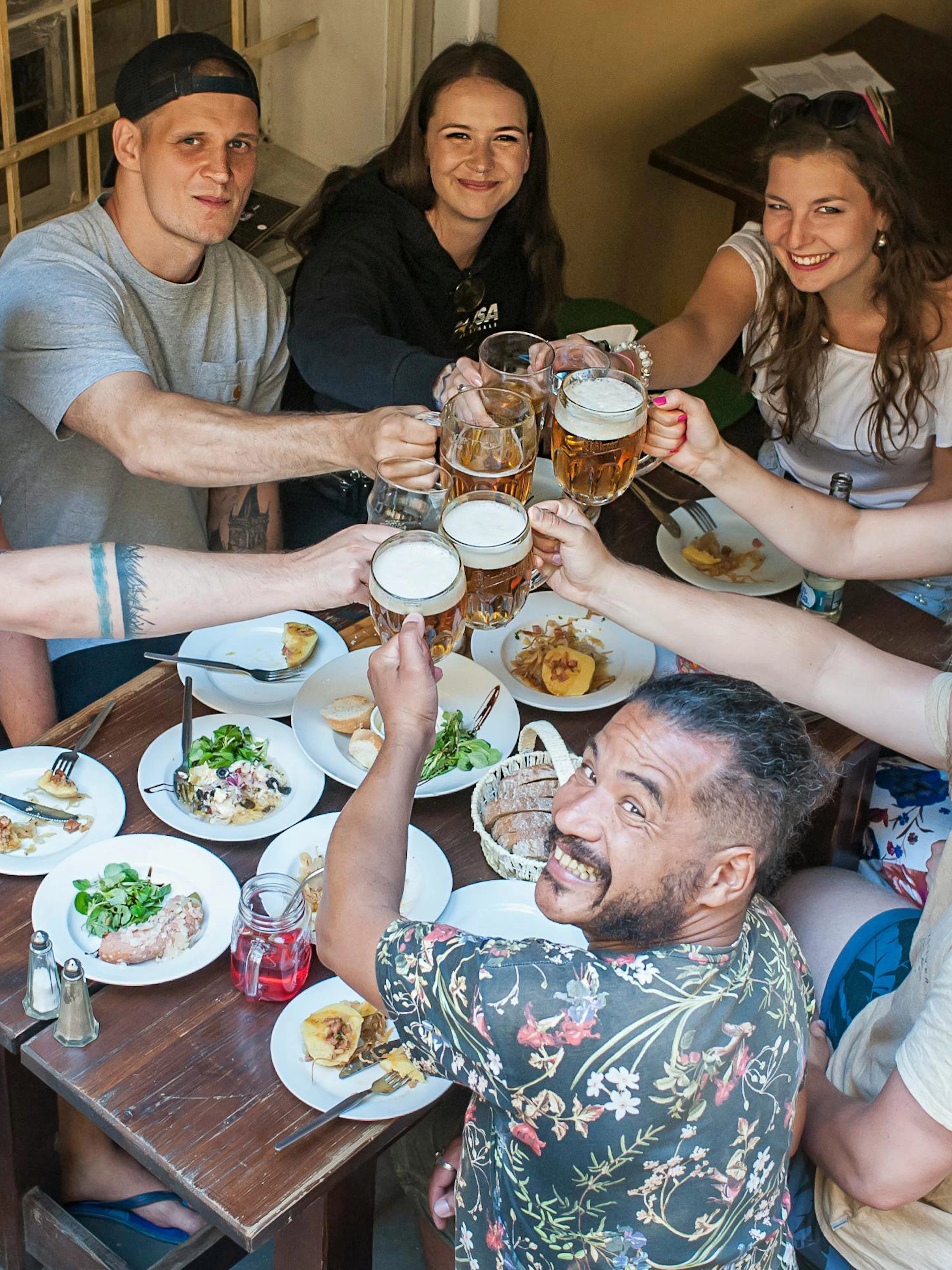 People enjoying Czech food and beer at a table on a Prague tour in Old Town.