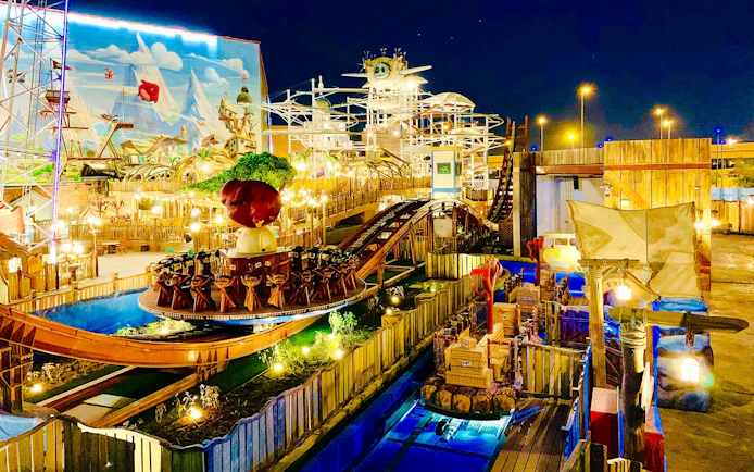 Disco coaster ride at night in Angry Birds World Theme Park, featuring vibrant lights and themed decor.