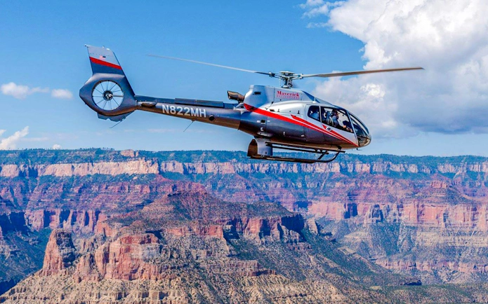 Helicopter flying over Grand Canyon South Rim during scenic tour.