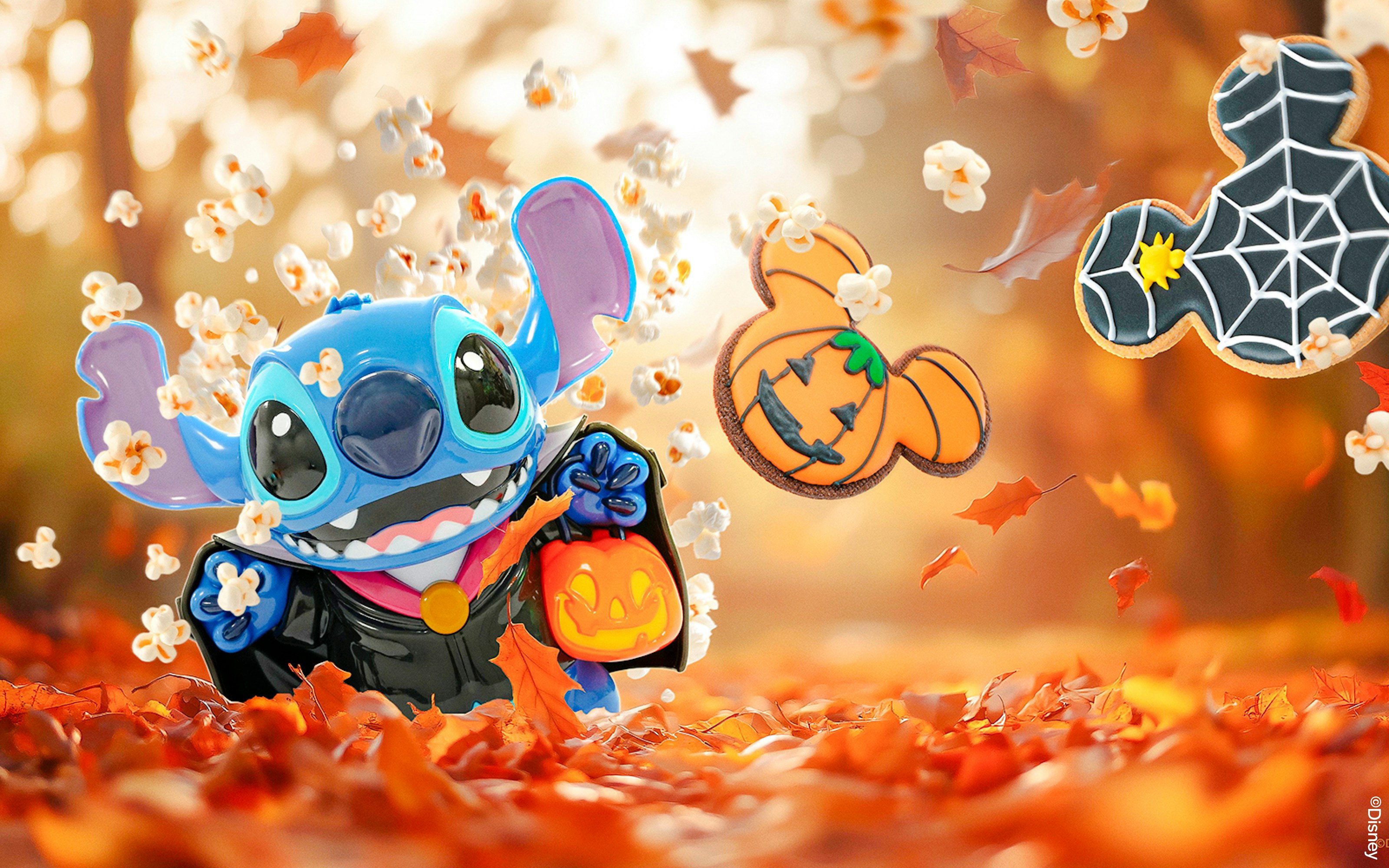 Stitch in Halloween costume with pumpkin bucket, surrounded by autumn leaves at Disneyland Paris.