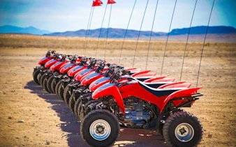 Red ATVs lined up on Las Vegas sand dunes for guided off-road tour.