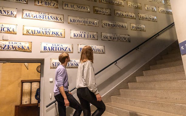 Couple exploring street signs inside Oskar Schindler's Factory, Krakow.