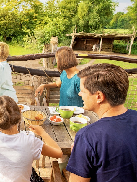 Family dining with view of zebras at Zoo Leipzig.