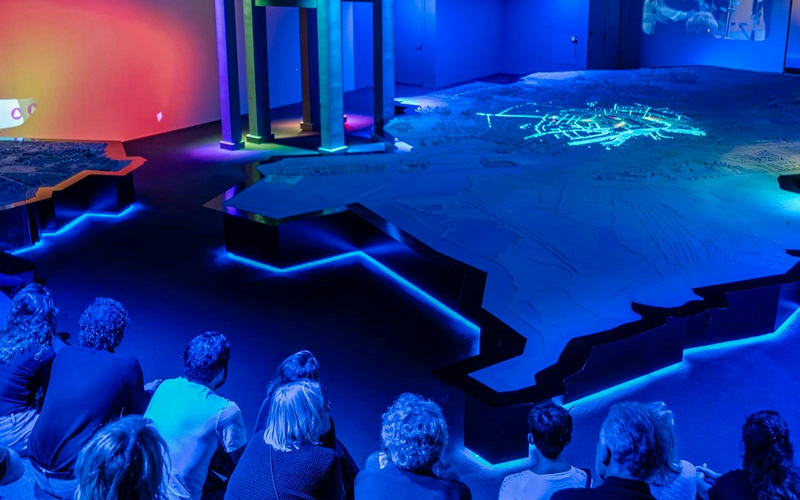 Visitors observing illuminated Amsterdam map at the Amsterdam in Motion exhibit.