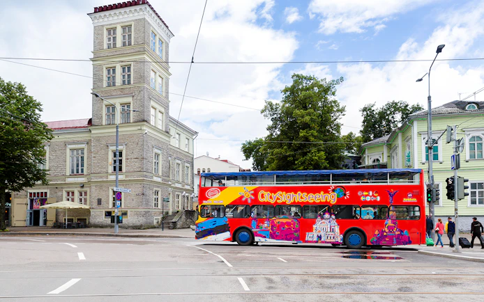 City sightseeing bus on a street in Tallinn near historic buildings.