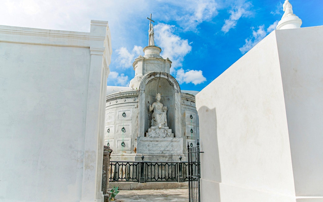 Tomb with statue and cross inside St. Louis Cemetery, New Orleans.