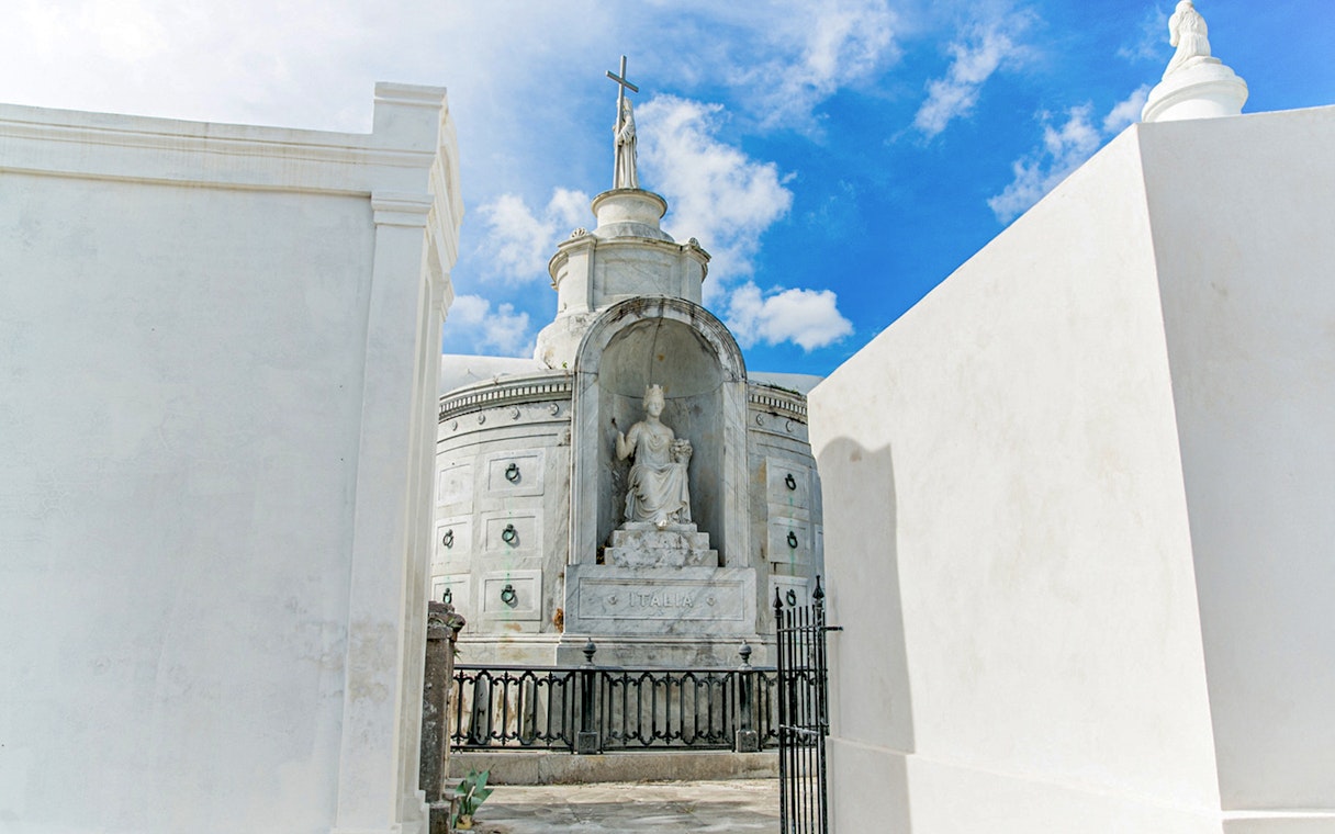 Tomb with statue and cross inside St. Louis Cemetery, New Orleans.