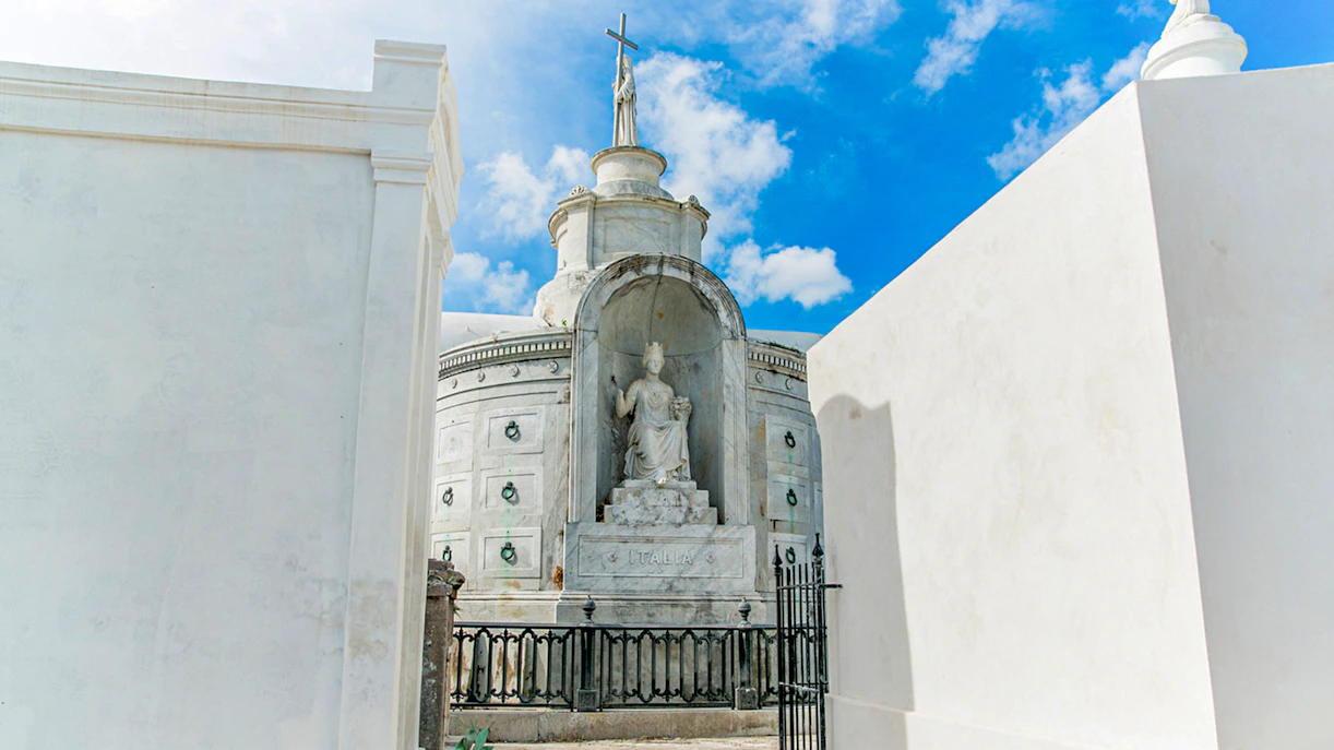 Tomb with statue and cross inside St. Louis Cemetery, New Orleans.