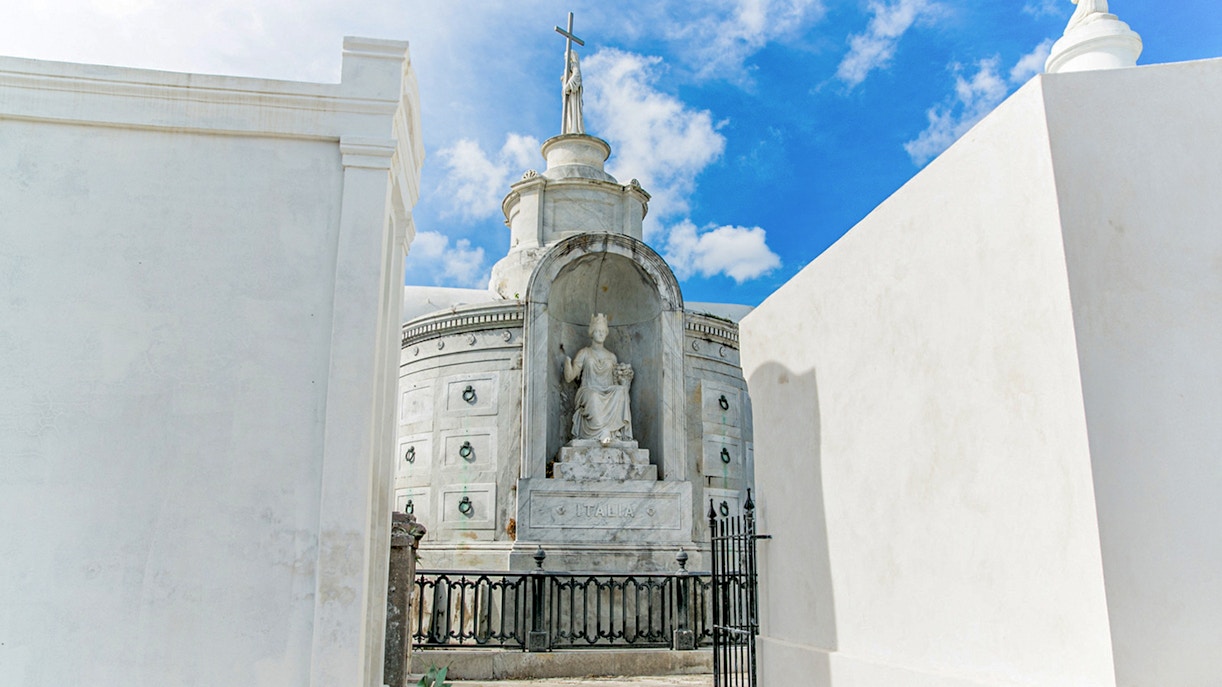 Tomb with statue and cross inside St. Louis Cemetery, New Orleans.