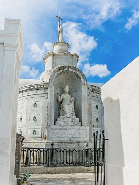 Tomb with statue and cross inside St. Louis Cemetery, New Orleans.