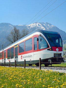 Train traveling through Lauterbrunnen with snow-capped mountains in the background.