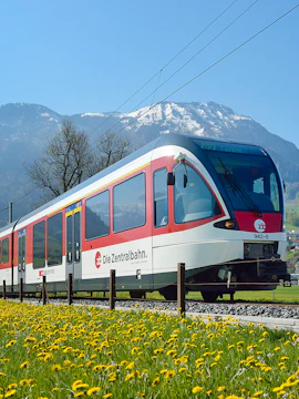 Train traveling through Lauterbrunnen with snow-capped mountains in the background.
