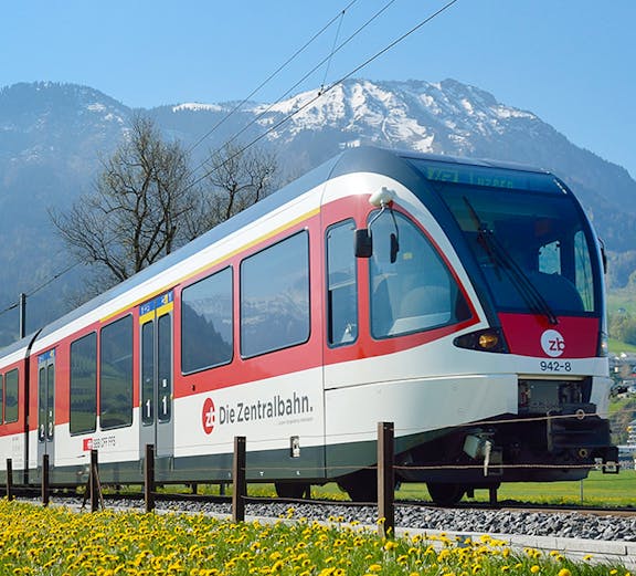 Train traveling through Lauterbrunnen with snow-capped mountains in the background.