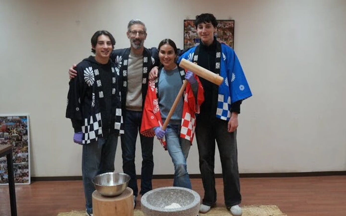 Group participating in Kyoto mochi pounding experience with traditional attire.
