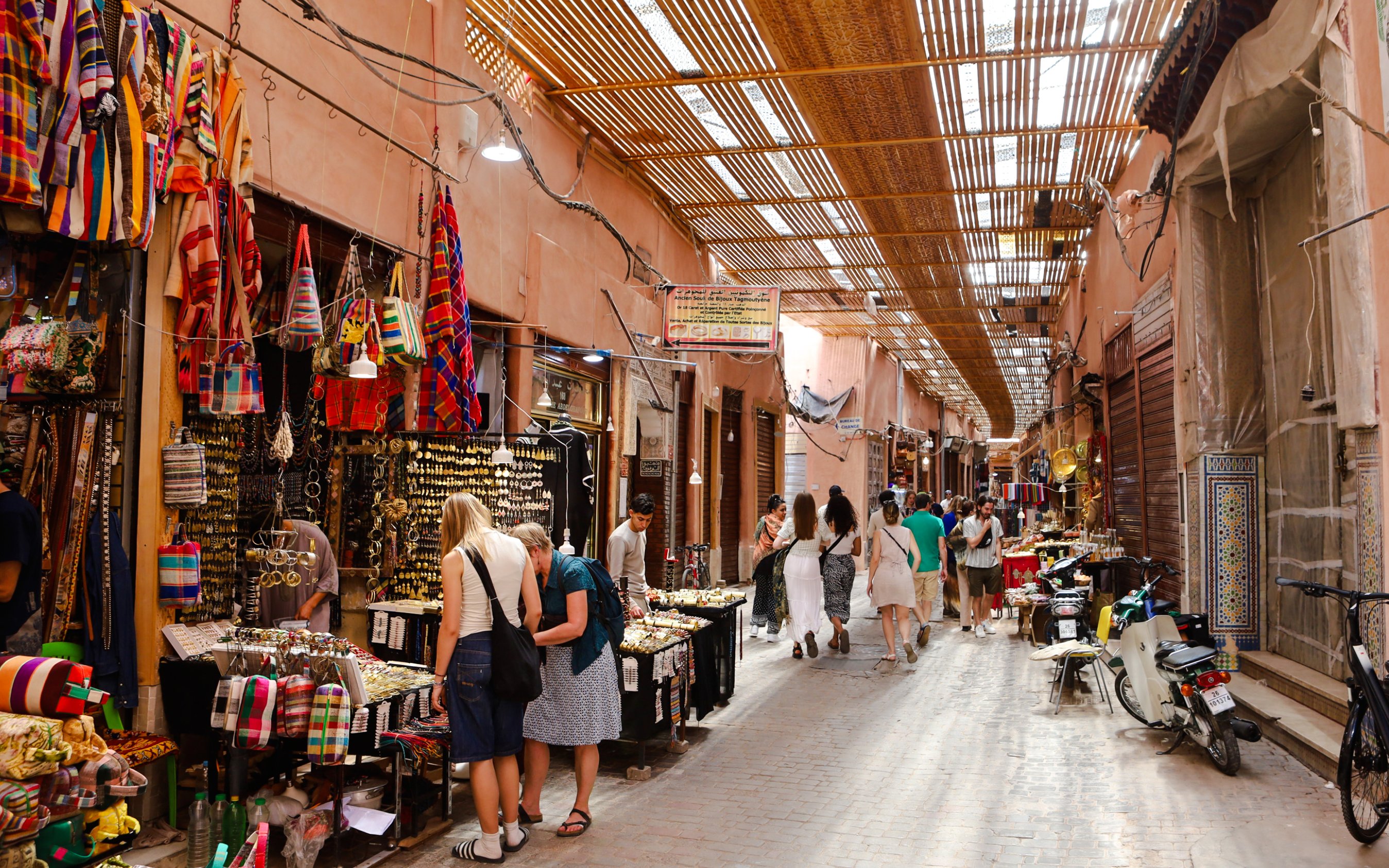 Visitors exploring vibrant stalls in Marrakech Souks, Morocco.