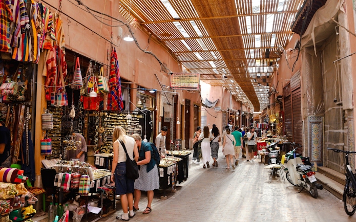 Visitors exploring vibrant stalls in Marrakech Souks, Morocco.