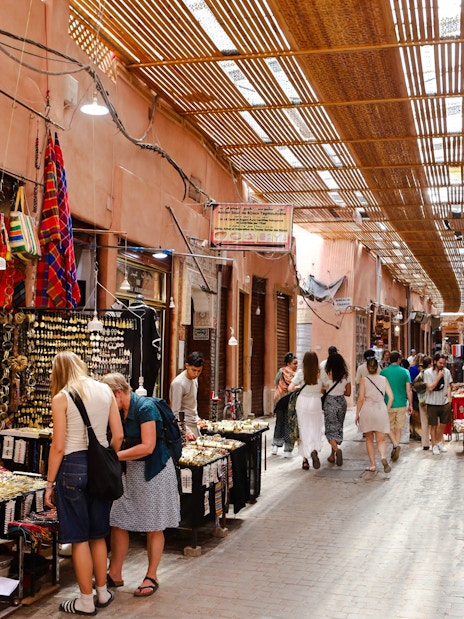 Visitors exploring vibrant stalls in Marrakech Souks, Morocco.