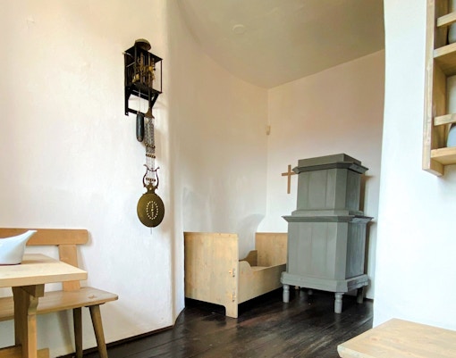 Watchmaker's Quarters interior with clock mechanism, wooden furniture, and stove in Nicholas Bell Tower, Prague.