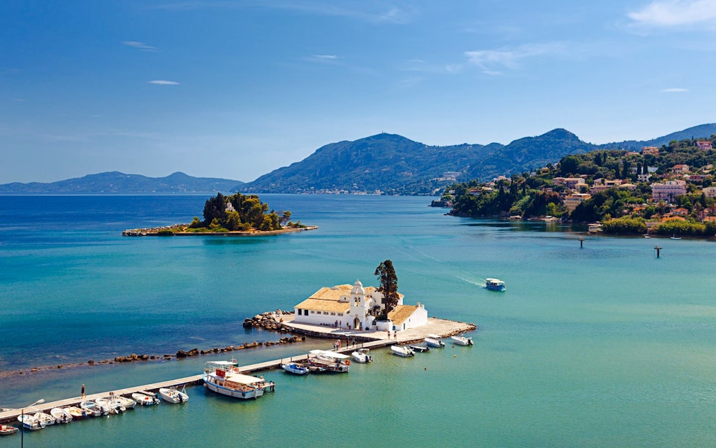 Mouse Island and Vlacherna Monastery in Corfu, Greece, with boats docked nearby.