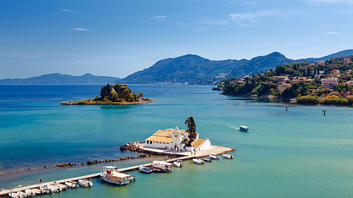 Mouse Island and Vlacherna Monastery in Corfu, Greece, with boats docked nearby.