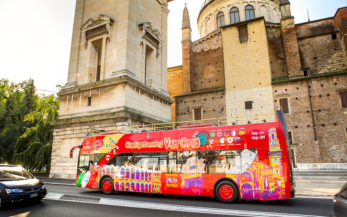 Verona sightseeing bus near historic building on hop-on hop-off tour.