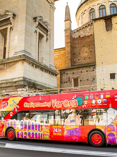 Verona sightseeing bus near historic building on hop-on hop-off tour.