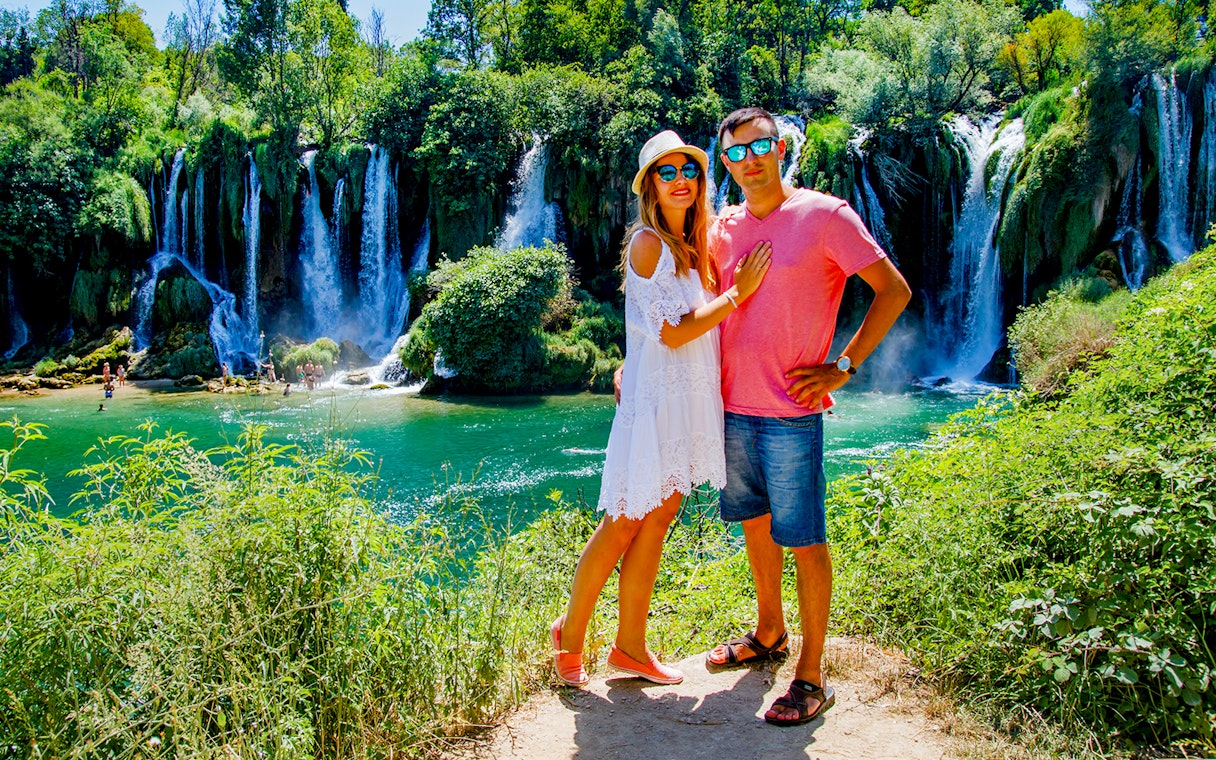 Couple standing in front of Kravica Waterfall during Mostar guided tour from Split to Trogir.