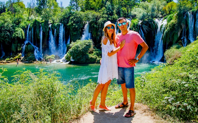 Couple standing in front of Kravica Waterfall during Mostar guided tour from Split to Trogir.
