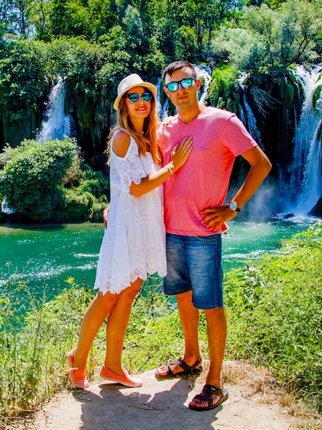 Couple standing in front of Kravica Waterfall during Mostar guided tour from Split to Trogir.