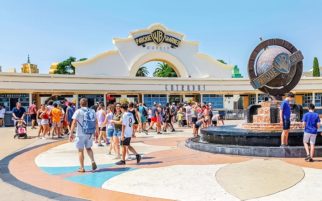Crowd at entrance of Parque Warner Madrid with fountain in foreground.