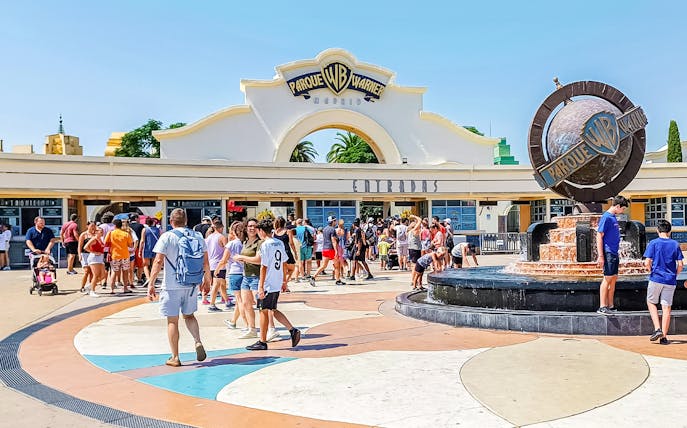 Crowd at entrance of Parque Warner Madrid with fountain in foreground.