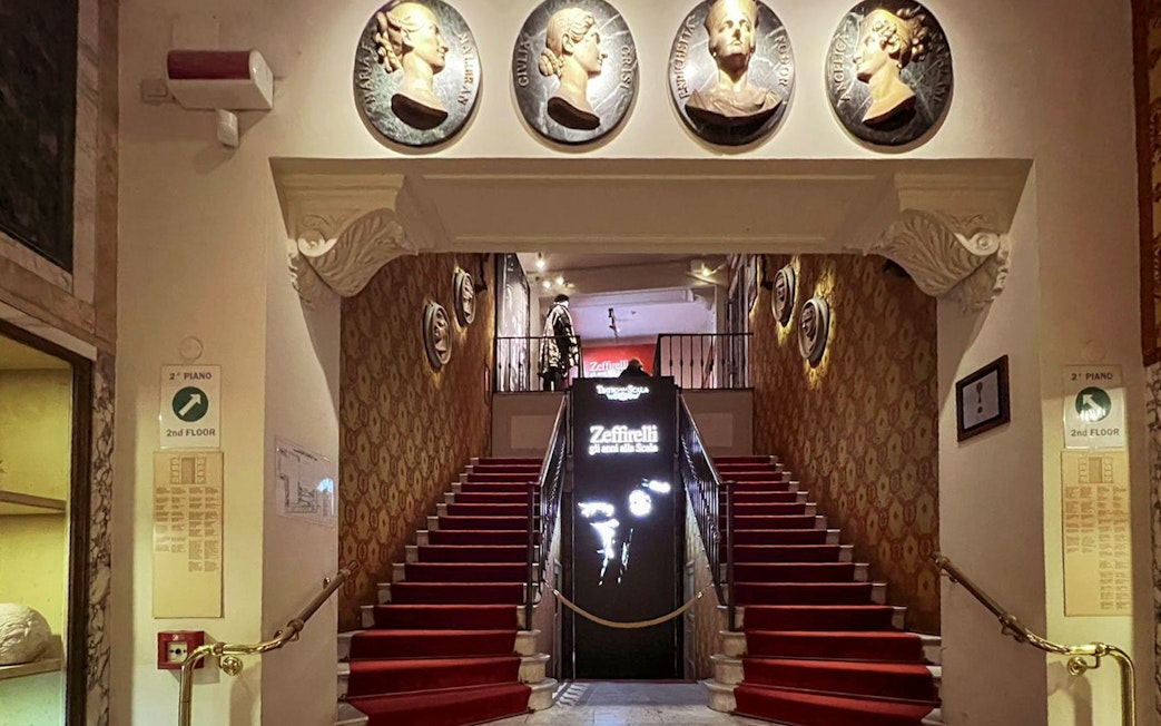 La Scala Theatre staircase with red carpet and decorative wall medallions in Milan, Italy.