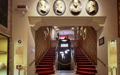 La Scala Theatre staircase with red carpet and decorative wall medallions in Milan, Italy.
