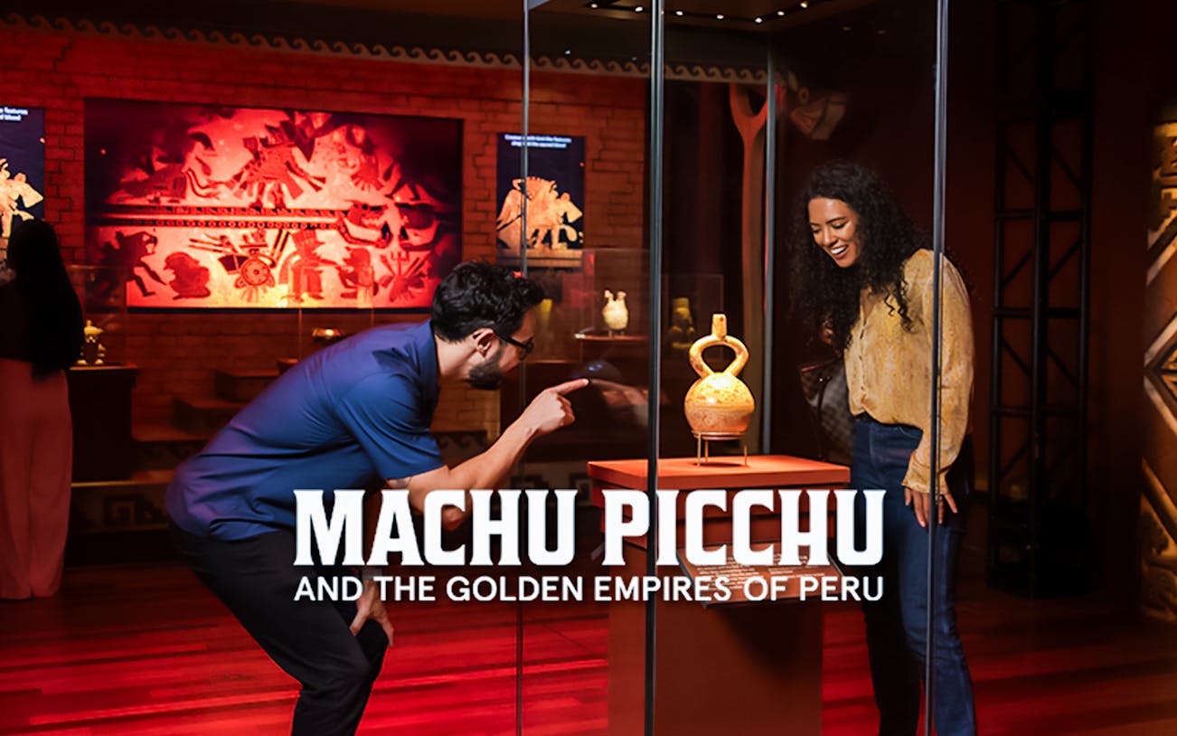 Visitors admire ancient Peruvian artifacts and multimedia displays at Machu Picchu exhibit.