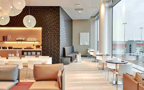 Amsterdam Schiphol Airport VIP lounge seating area with modern decor and large windows.