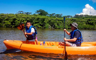 Kayaking on a river at Ishigaki Yaima Village with lush greenery in the background.