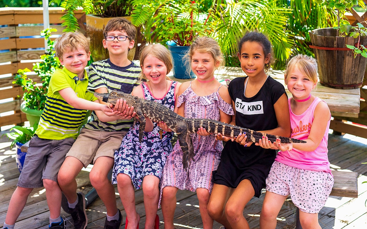 Children holding a small alligator during Everglades airboat tour experience.