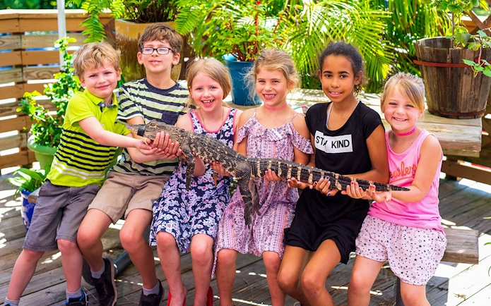 Children holding a small alligator during Everglades airboat tour experience.