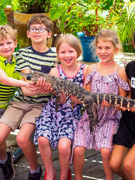 Children holding a small alligator during Everglades airboat tour experience.