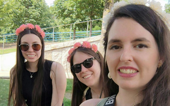 Three people wearing flower crowns enjoying a sunny day in a park in Madrid.