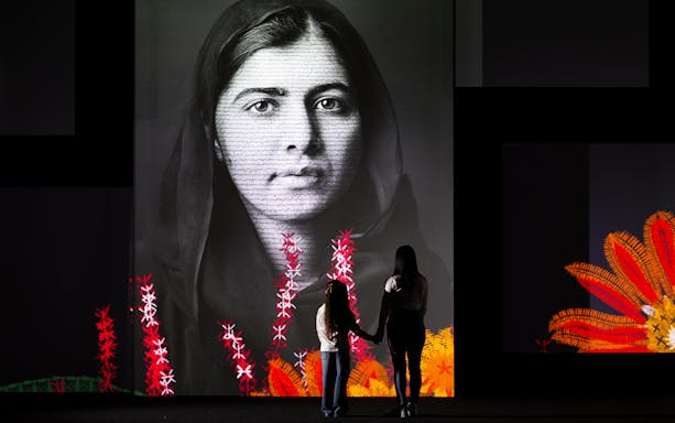 Visitors viewing a large portrait at the Frameless National Portrait Gallery Exhibition.